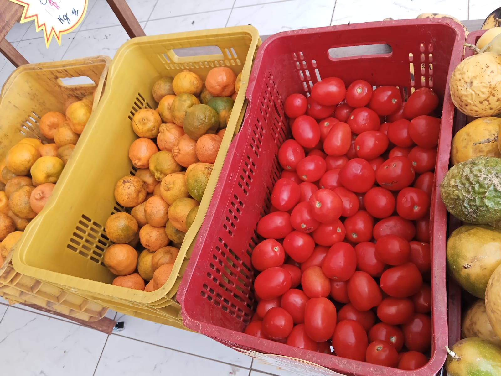 Caixas com laranjas e tomates frescos